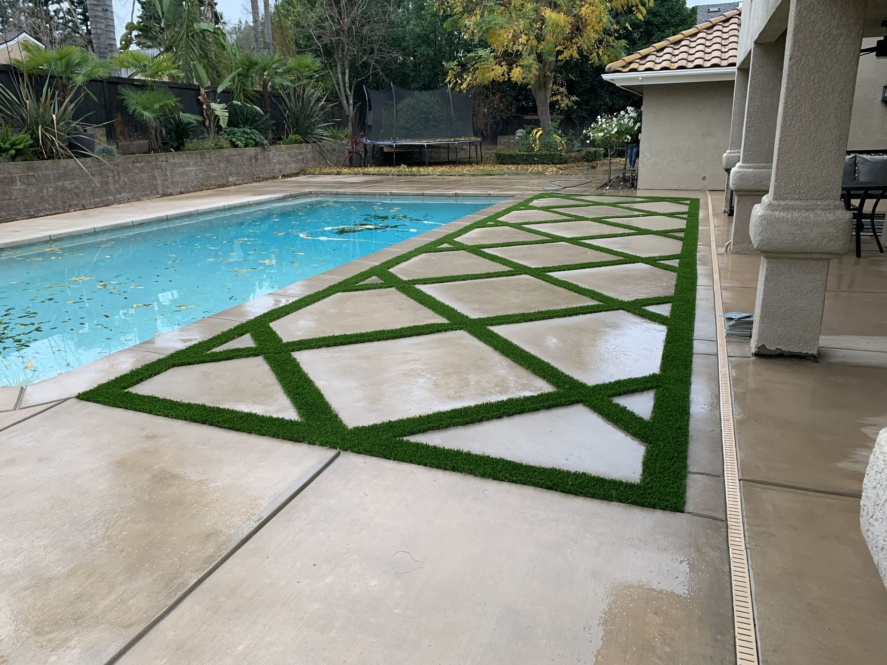 Diamond pattern turf and concrete grid running alongside a pool