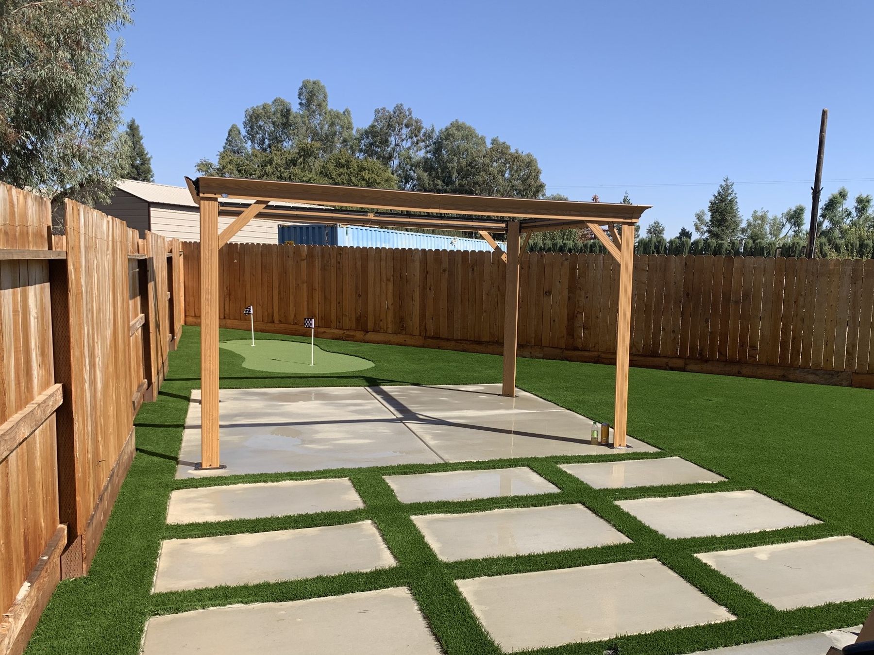 Cedar pergola over a paver and turf grid with a putting green