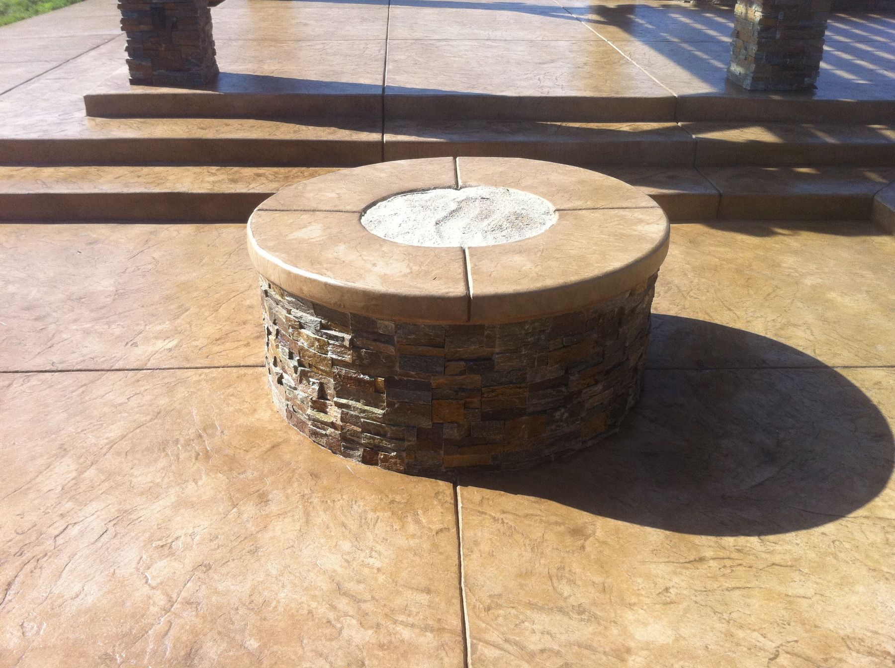 Round stone fire pit on a stamped concrete patio
